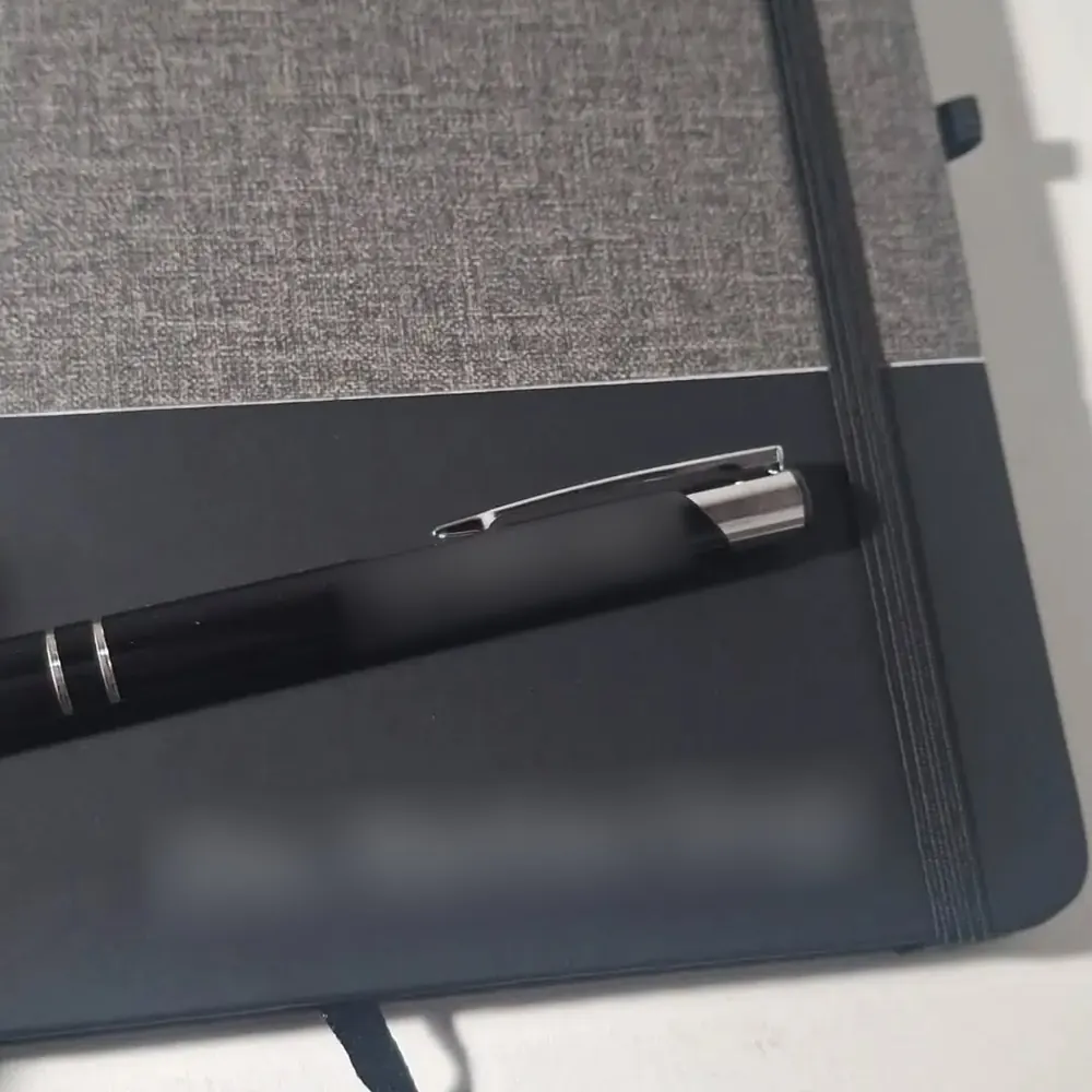 Cuaderno negro grabado en la tapa, con la lapicera haciendo juego
